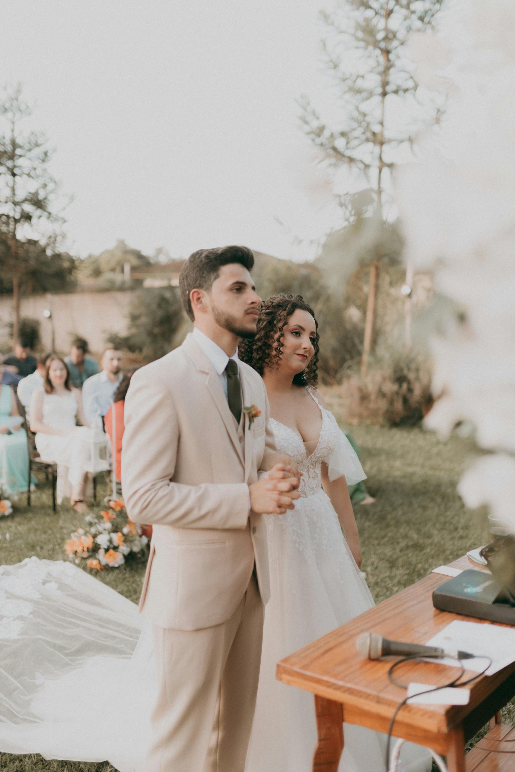 Bride and groom stand together during an elegant outdoor wedding ceremony.